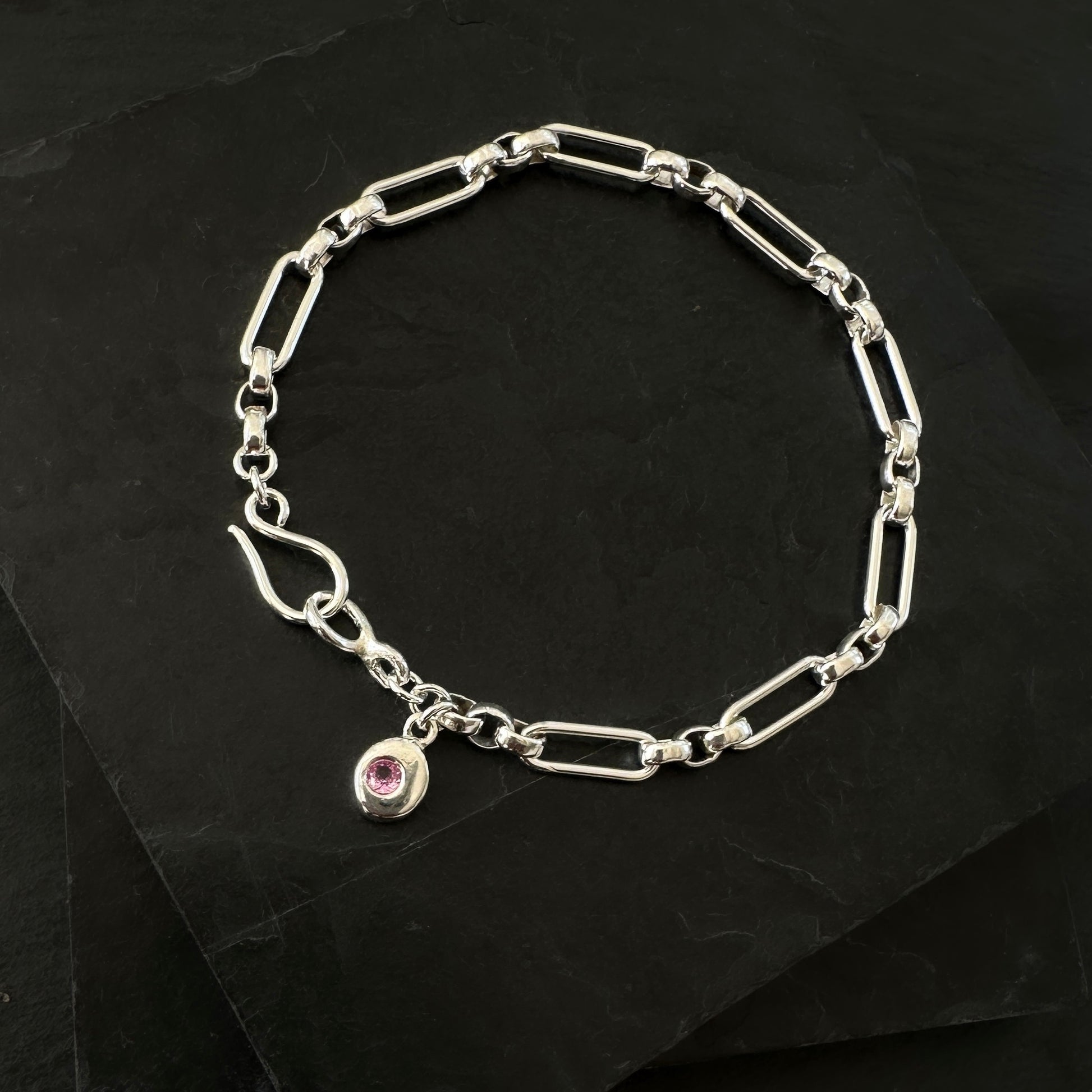 Silver bracelet with a small pink gemstone charm 