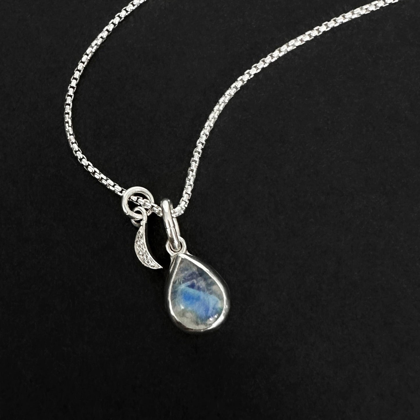 Silver necklace with a teardrop-shaped moonstone pendant on a black background