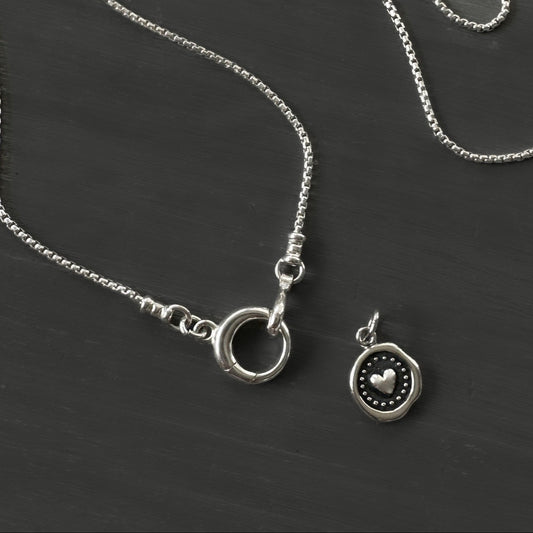 Silver necklace with a heart pendant on a dark surface
