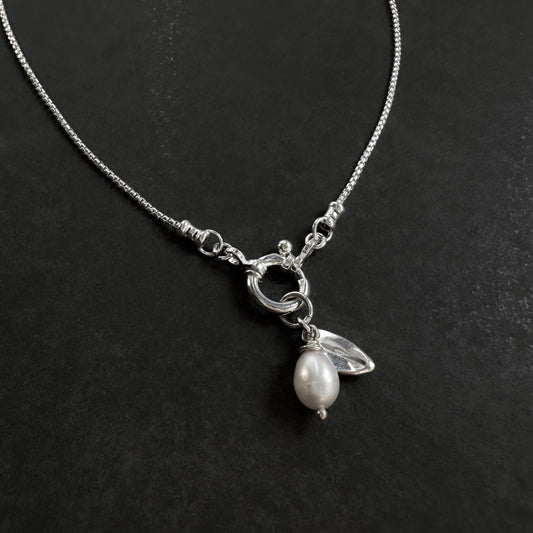 Silver necklace with a pearl pendant on a black background