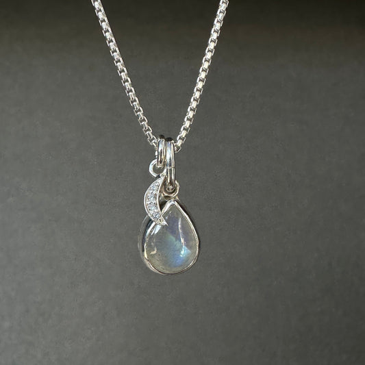 Silver necklace with a teardrop-shaped pendant on a dark gray background