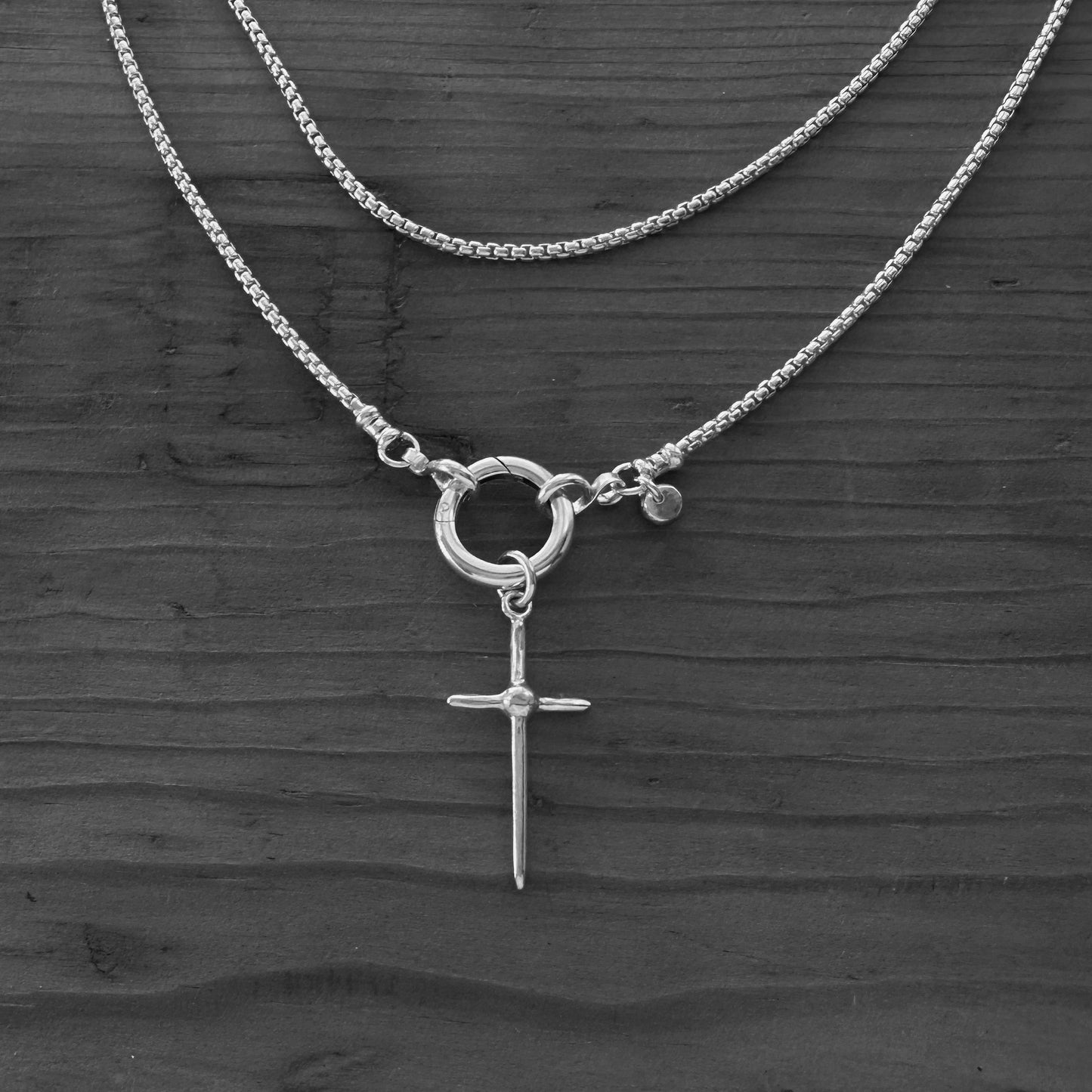 Silver necklace with a cross pendant on a dark wooden surface