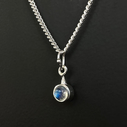 Silver necklace with a moonstone pendant on a black background