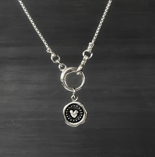 Silver necklace with a heart pendant on a dark background