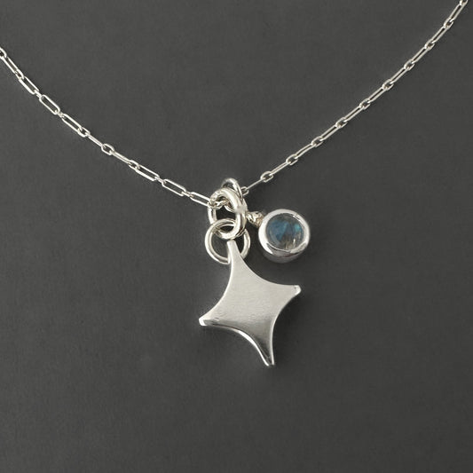 Silver necklace with a note star-shaped pendant and rainbow moonstone round charm on a dark background