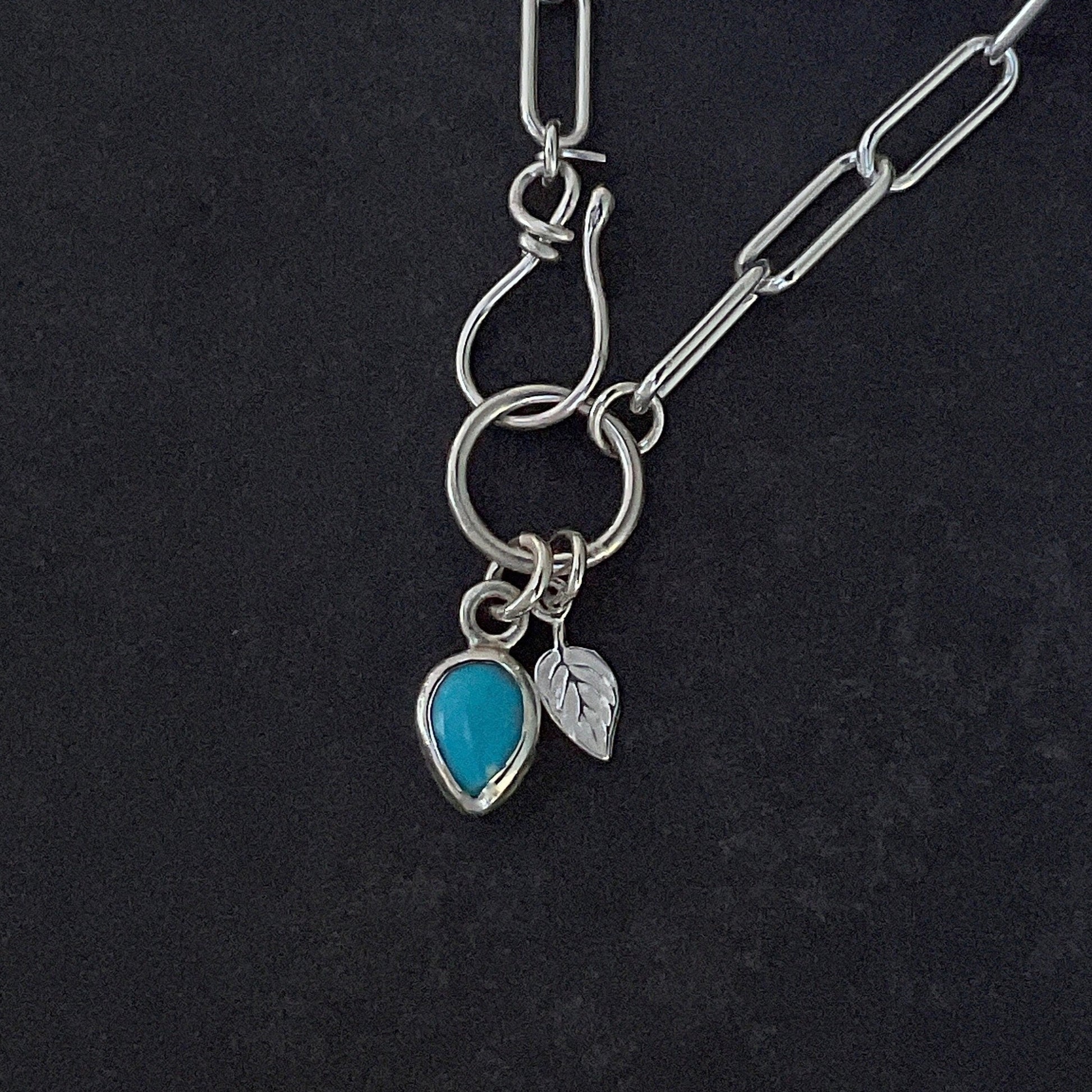 Turquoise Charm Necklace Kingman Blue Turquoise Teardrop Charm 9x6mm next to a tiny leaf charm Necklace Sterling Silver Paperclip Chain Necklace 4.3mm width with a front closure hook and ring clasp